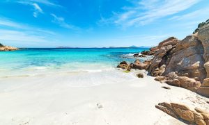 a picture of some scattered rocks at spiaggia capriccioli in costa smeralda sardinia