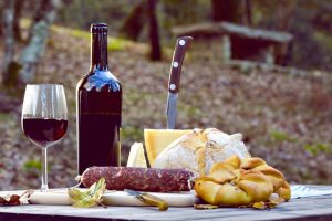 a picture of a typical Sardinian dinner made of cheese, sausage, bread and wine.