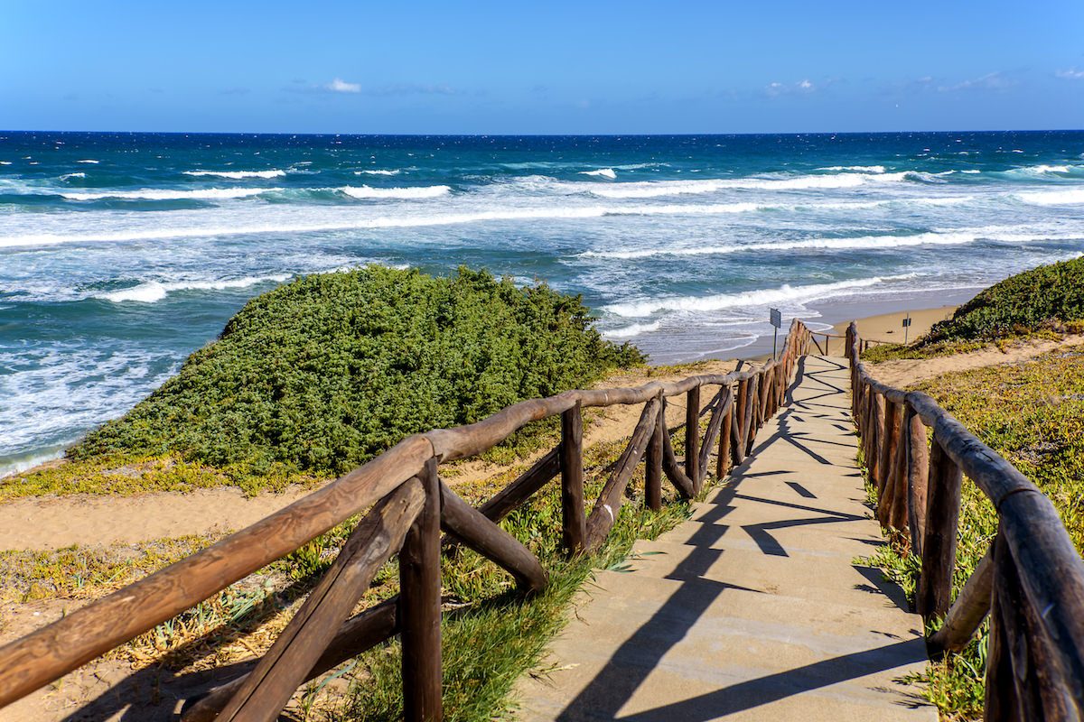 a picture of the wooden pathway that leads to the beach named Spiaggia di Lu Bagnu, near Castelsardo, north Sardinia, Italy.