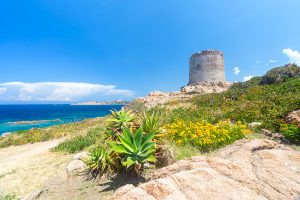 a picture of the coastline of Isola Rossa in north Sardinia, Italy. In the background it features the ancient watchtower named Torre Aragonese.