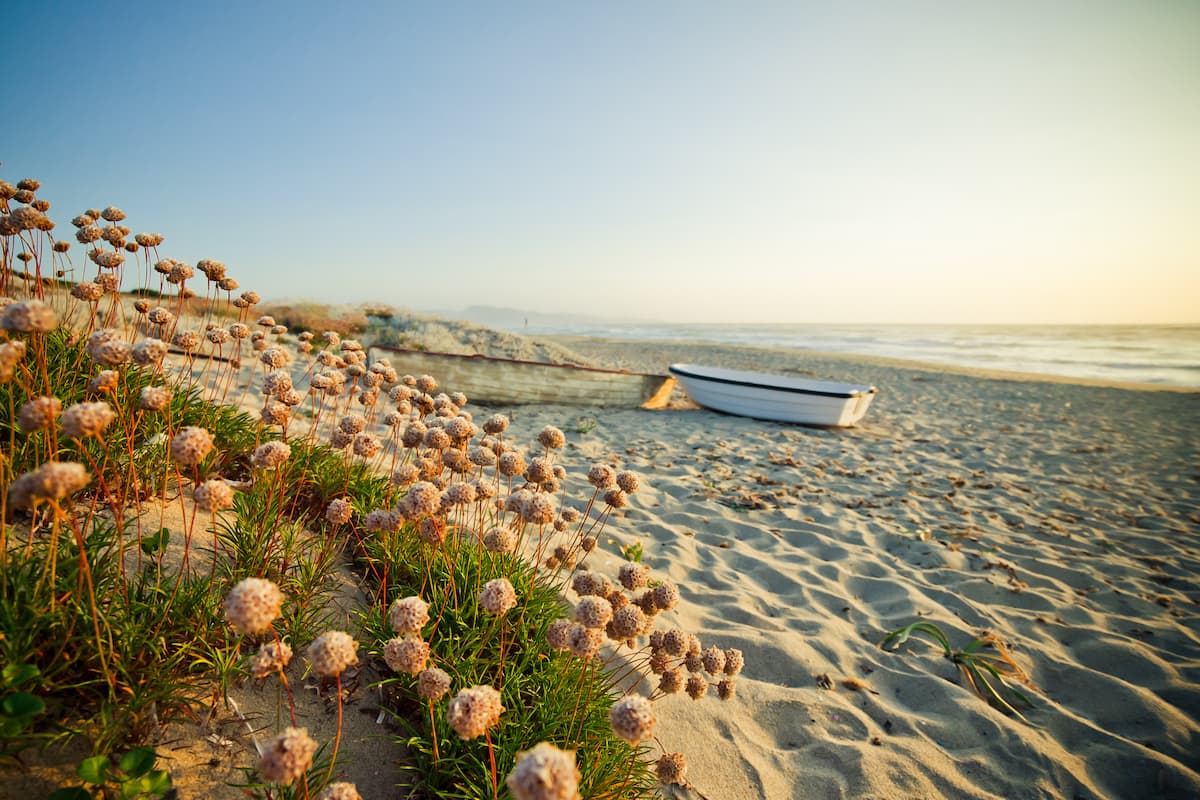 a small boat rests on the sands of a beach near Badesi, north Sardinia, Italy.