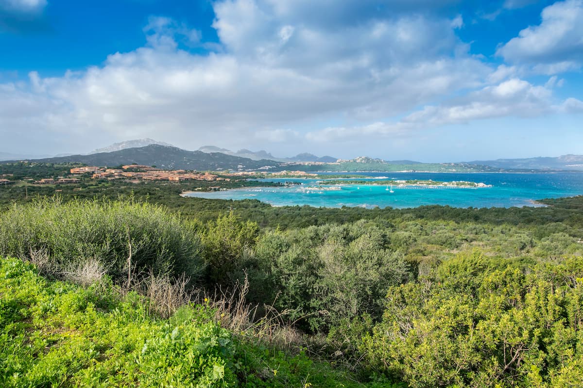 deep blue waters and lush green hills near Golfo di Marinella, on the Emerald Coast in north-east Sardinia, Italy.