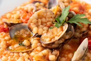 a dish of sardinian fregola with clam and tomato sauce