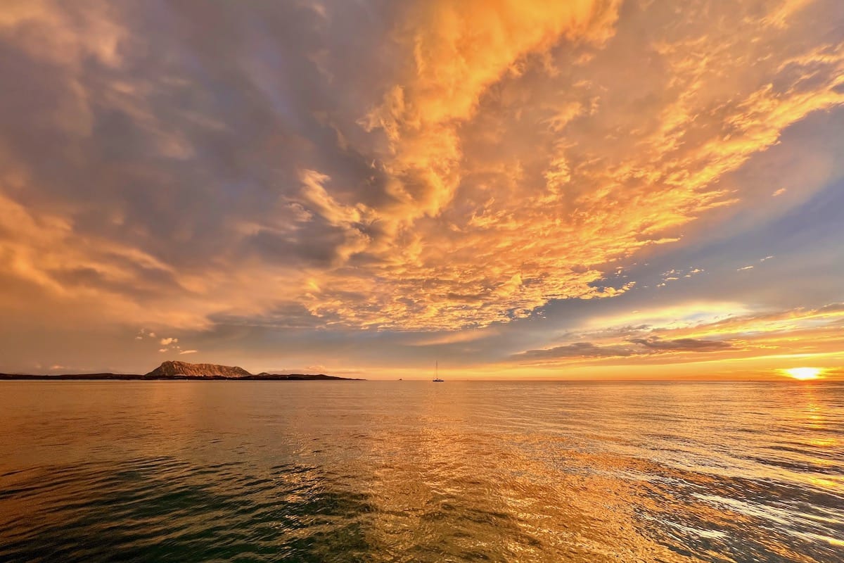 an unforgettable sunrise over Isola Tavolara in September 2022. This picture was taken with an iPhone from a boat in the waters of Spiaggia La Cinta near San Teodoro, Sardinia.