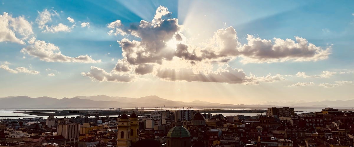 The sun breaking through the clouds over the city of Cagliari, Italy in September 2021.