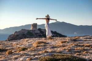 A woman enjoying the view of Torre del Porticciolo on the coast of Alghero, northwest Sardinia, Italy.